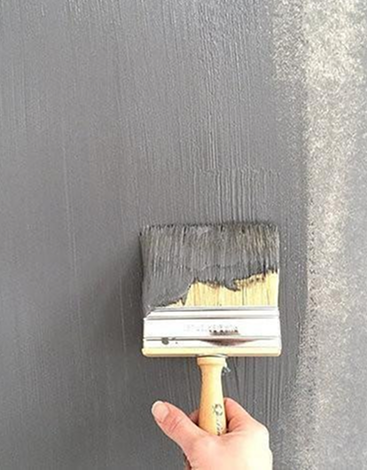 Brush applying grey textured cement paint